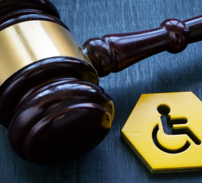 Zdjęcie młotka sędziowskiego obok plakietka z symbolem niepełnosprawności.