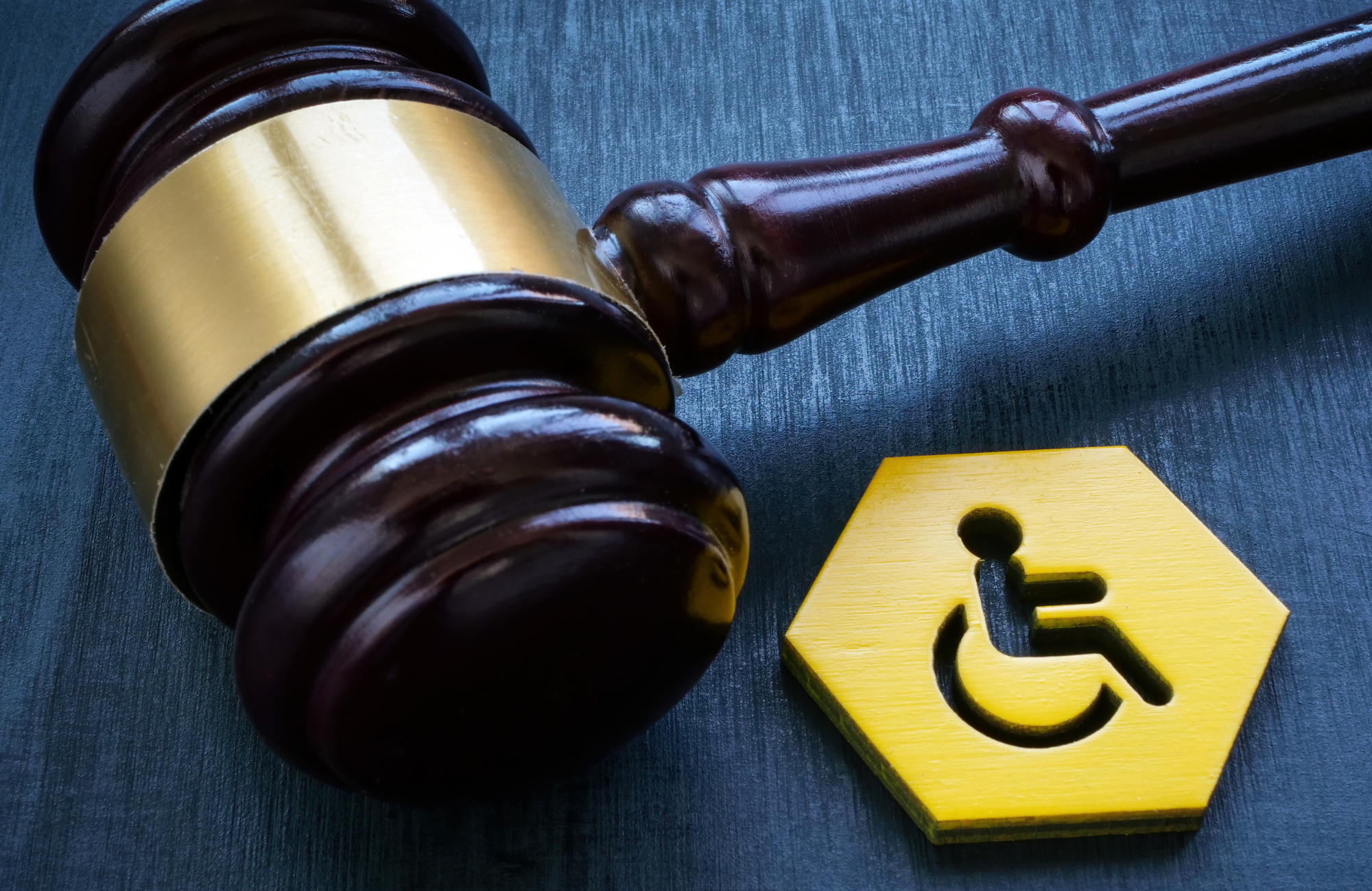 Zdjęcie młotka sędziowskiego obok plakietka z symbolem niepełnosprawności.